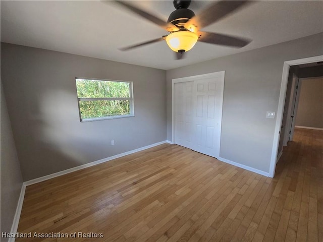 unfurnished bedroom with ceiling fan, a closet, and light wood-type flooring