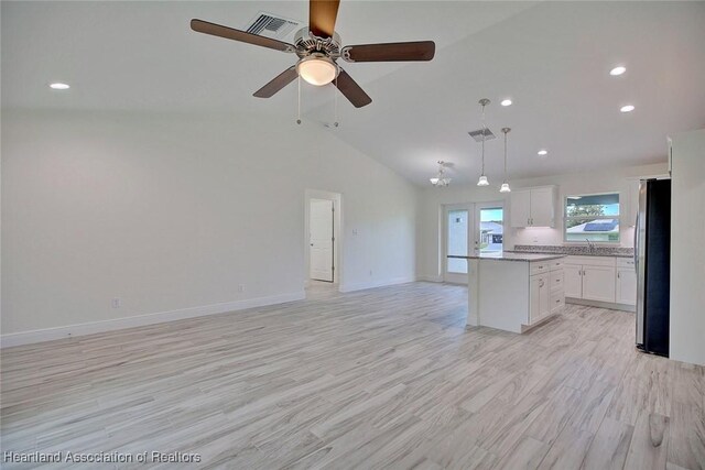 kitchen with white cabinetry, a center island, ceiling fan, hanging light fixtures, and stainless steel fridge