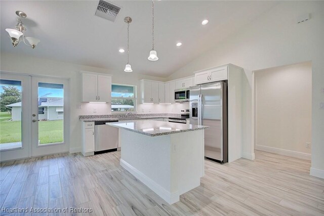 kitchen featuring a center island, light hardwood / wood-style flooring, decorative light fixtures, white cabinetry, and stainless steel appliances