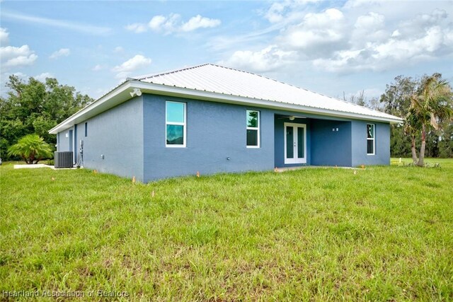 rear view of property with a lawn, central air condition unit, and french doors