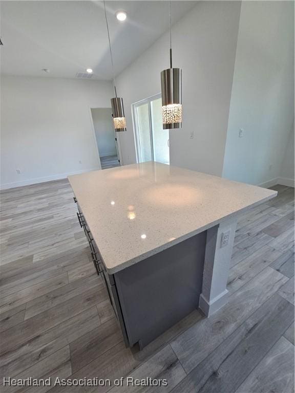 kitchen with pendant lighting, hardwood / wood-style flooring, and a kitchen island