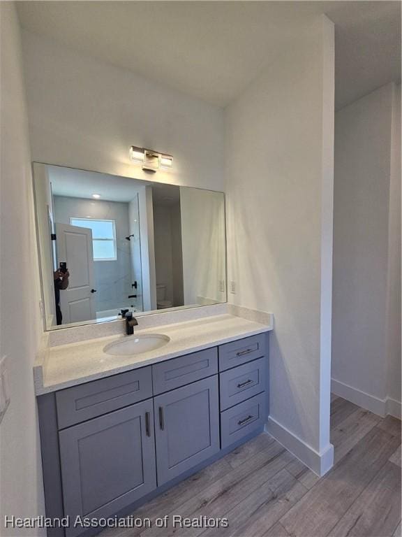 bathroom featuring toilet, vanity, wood-type flooring, and walk in shower