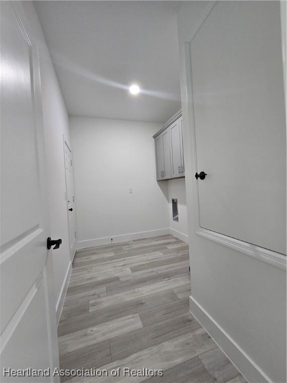 clothes washing area featuring light hardwood / wood-style floors and cabinets