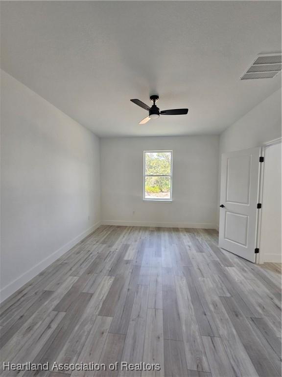 empty room with ceiling fan and light hardwood / wood-style floors