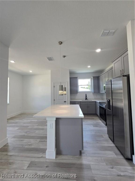 kitchen featuring gray cabinetry, stainless steel appliances, sink, a center island, and hanging light fixtures