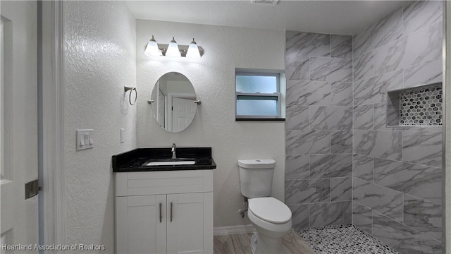 bathroom featuring vanity, toilet, and tiled shower