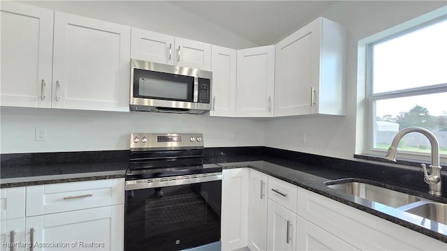 kitchen featuring range with electric cooktop, sink, dark stone countertops, and white cabinets