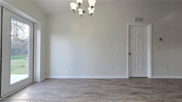 unfurnished room featuring hardwood / wood-style flooring, a healthy amount of sunlight, and an inviting chandelier