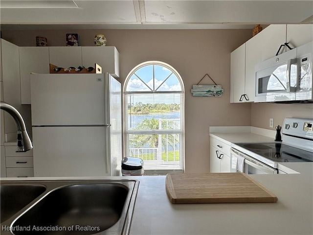 kitchen with white cabinets, white appliances, light countertops, and a sink