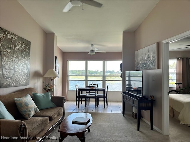 living area with a wealth of natural light, light carpet, a ceiling fan, and light tile patterned flooring