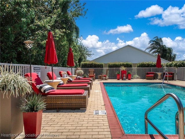 community pool with a patio area and fence