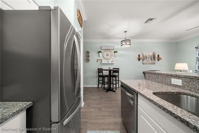 kitchen with visible vents, dark wood finished floors, ornamental molding, stainless steel appliances, and white cabinetry
