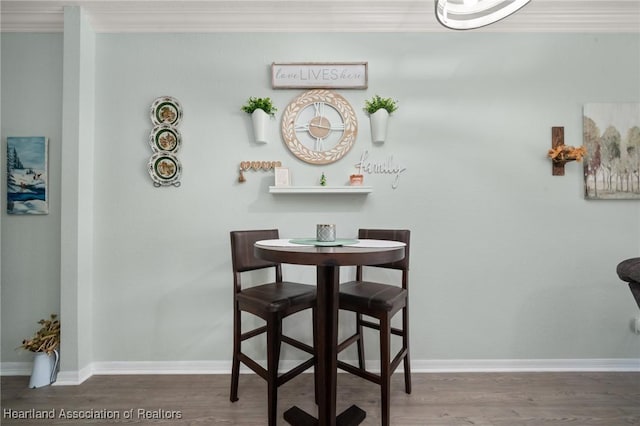 dining room with ornamental molding, baseboards, and wood finished floors