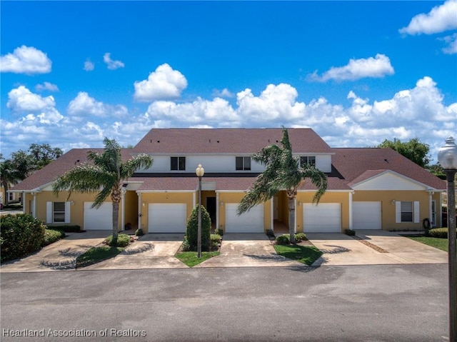 view of property with stucco siding, driveway, an attached garage, and roof with shingles