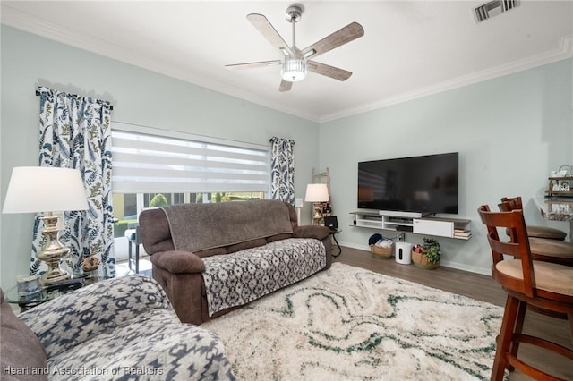 living room with visible vents, crown molding, baseboards, ceiling fan, and wood finished floors