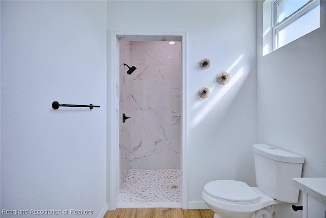 bathroom featuring a marble finish shower, toilet, and wood finished floors