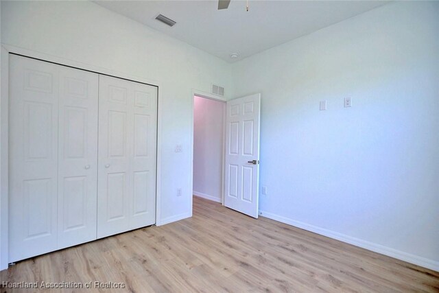unfurnished bedroom featuring baseboards, visible vents, a closet, and wood finished floors