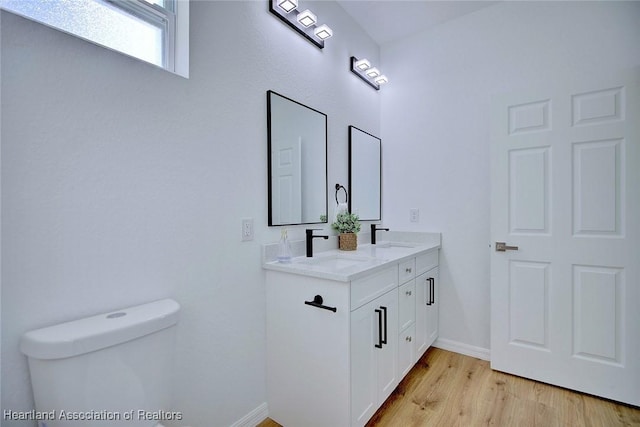bathroom featuring a sink, baseboards, wood finished floors, and toilet