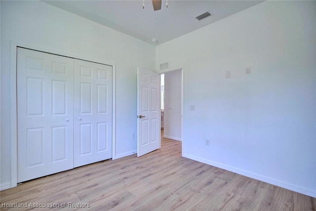 unfurnished bedroom featuring wood finished floors, a closet, and visible vents