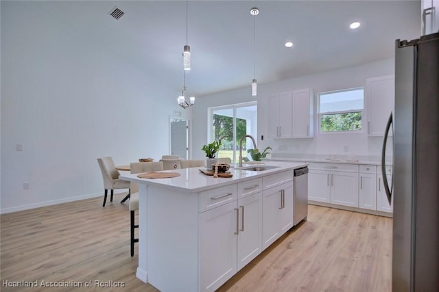 kitchen featuring white cabinets, stainless steel appliances, a notable chandelier, and a wealth of natural light