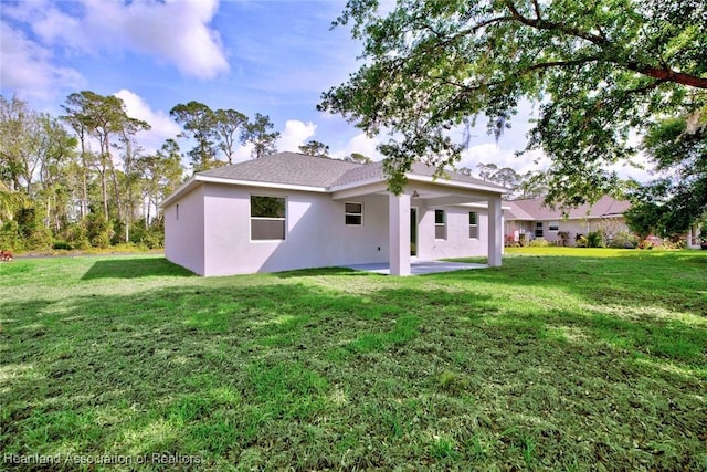rear view of property featuring stucco siding, a yard, and a patio