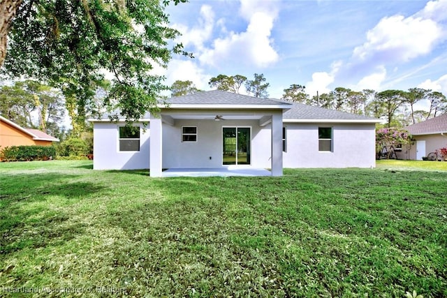 rear view of house with a lawn, stucco siding, and a patio area