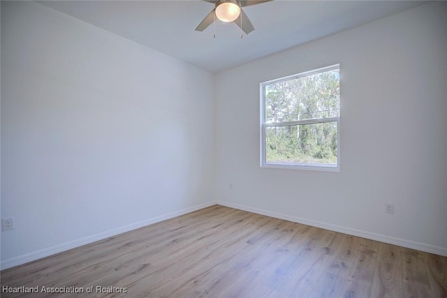 empty room with baseboards, wood finished floors, and a ceiling fan