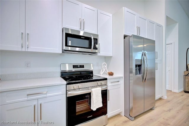kitchen with white cabinetry, light countertops, light wood finished floors, and appliances with stainless steel finishes