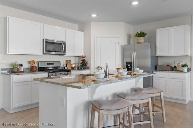 6856 Coconut Dr, Sebring, FL 33872 - kitchen with stainless steel appliances, light stone counters, a sink, a kitchen island with sink, and white cabinets