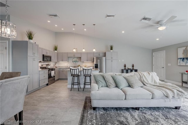 living area featuring high vaulted ceiling, visible vents, and ceiling fan with notable chandelier