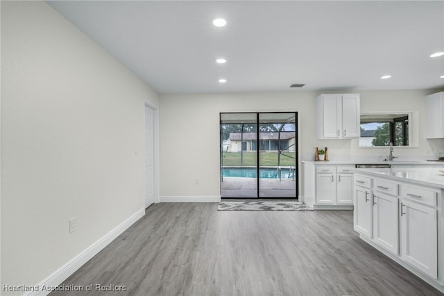 kitchen featuring white cabinets, light wood-type flooring, and sink