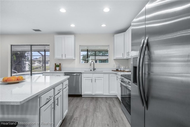 kitchen featuring stainless steel appliances, light hardwood / wood-style floors, white cabinets, and sink