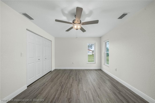 unfurnished bedroom featuring ceiling fan, dark wood-type flooring, and a closet