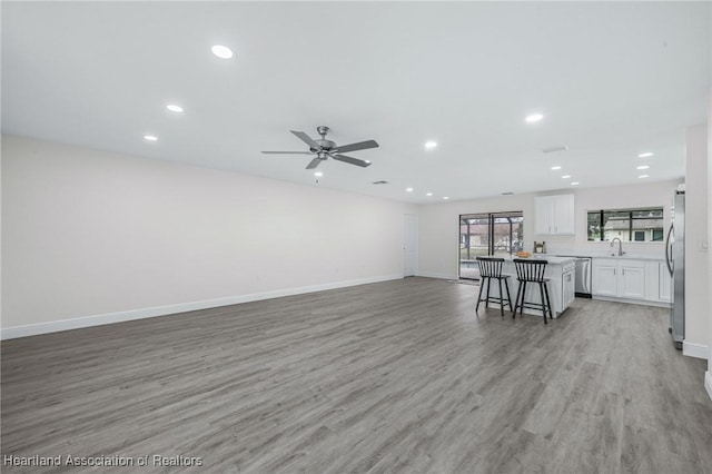 unfurnished living room with ceiling fan, light hardwood / wood-style flooring, and sink