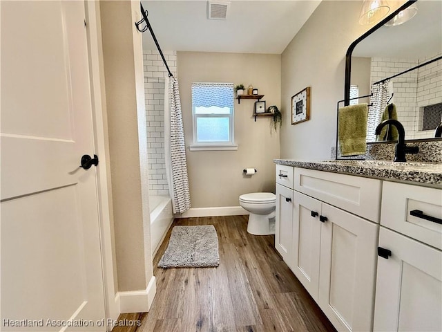 bathroom featuring visible vents, toilet, vanity, wood finished floors, and baseboards