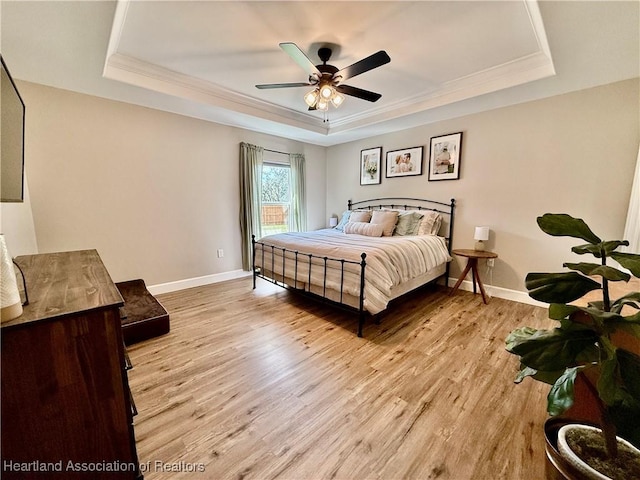 bedroom with crown molding, a raised ceiling, ceiling fan, light wood-type flooring, and baseboards