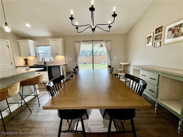 dining room featuring a chandelier, vaulted ceiling, and light wood-style flooring