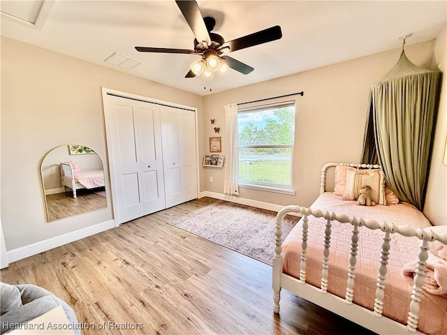 bedroom with visible vents, baseboards, a ceiling fan, wood finished floors, and a closet