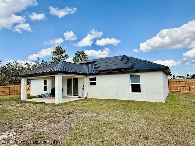 rear view of house featuring a yard, metal roof, a fenced backyard, and a patio