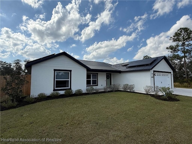 ranch-style house with a garage, driveway, metal roof, roof mounted solar panels, and a front lawn