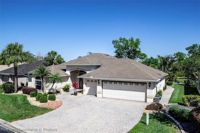 single story home featuring stucco siding, a front yard, decorative driveway, and a garage