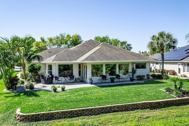 rear view of house featuring a patio, a lawn, and stucco siding