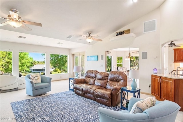 living room with arched walkways, visible vents, light carpet, and ceiling fan