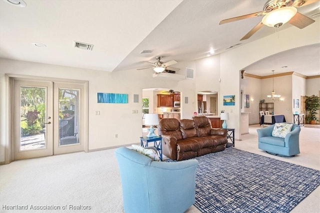 carpeted living area featuring visible vents, arched walkways, crown molding, baseboards, and ceiling fan