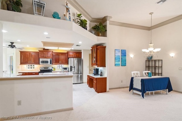 kitchen with ornamental molding, decorative light fixtures, stainless steel appliances, light countertops, and light colored carpet