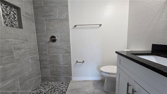 bathroom featuring vanity, toilet, and a tile shower