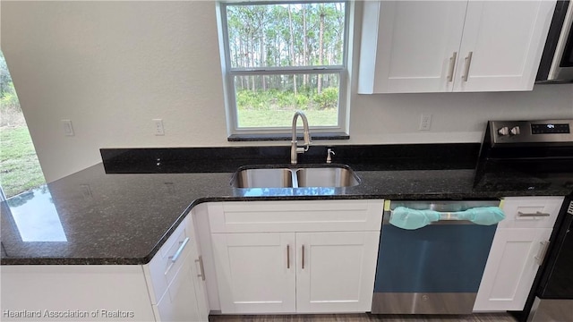 kitchen featuring white cabinetry, sink, stainless steel appliances, and dark stone counters