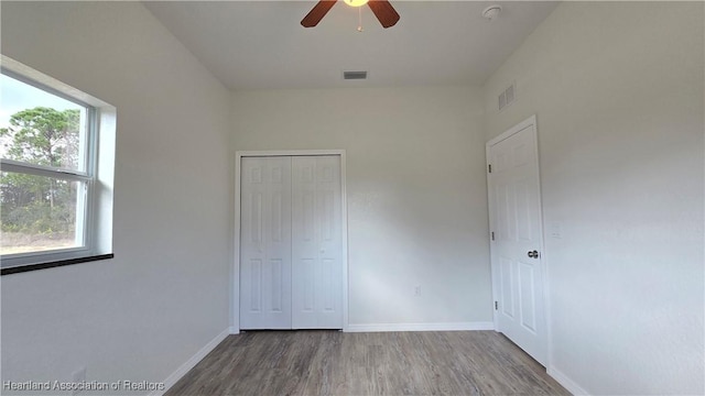 unfurnished bedroom featuring hardwood / wood-style flooring, ceiling fan, and a closet