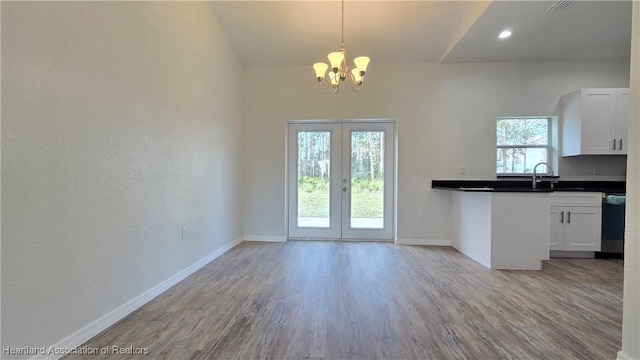 kitchen featuring french doors, sink, white cabinetry, light hardwood / wood-style flooring, and pendant lighting