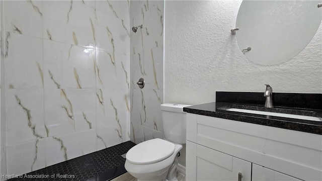 bathroom featuring tiled shower, vanity, and toilet